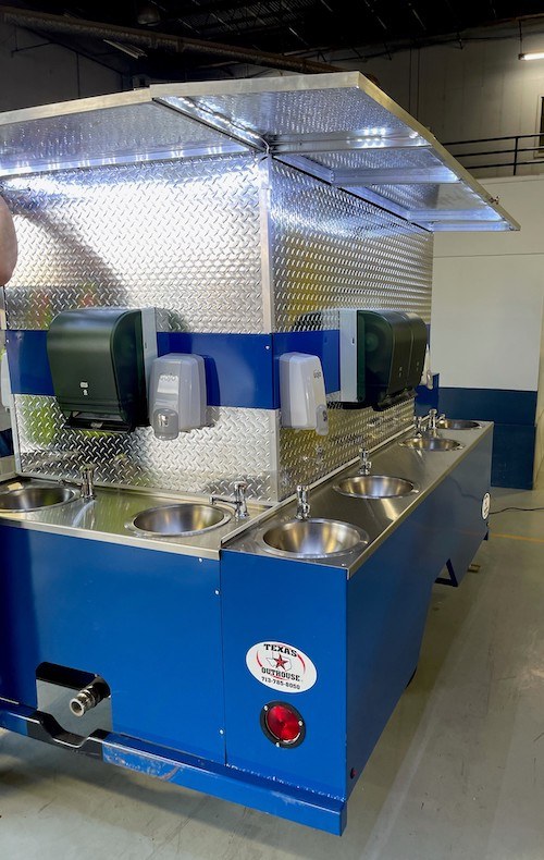 A portable sink with hot water provided by Texas Outhouse is in use at an event