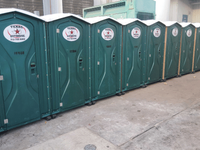 Row of portable toilets from Texas Outhouse lined up outside of a job site